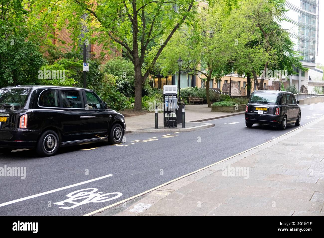 Schwarzes Taxi zum Aufladen des Fahrzeugs an einer elektrischen Ladestation in der City of London England, Großbritannien, KATHY DEWITT Stockfoto