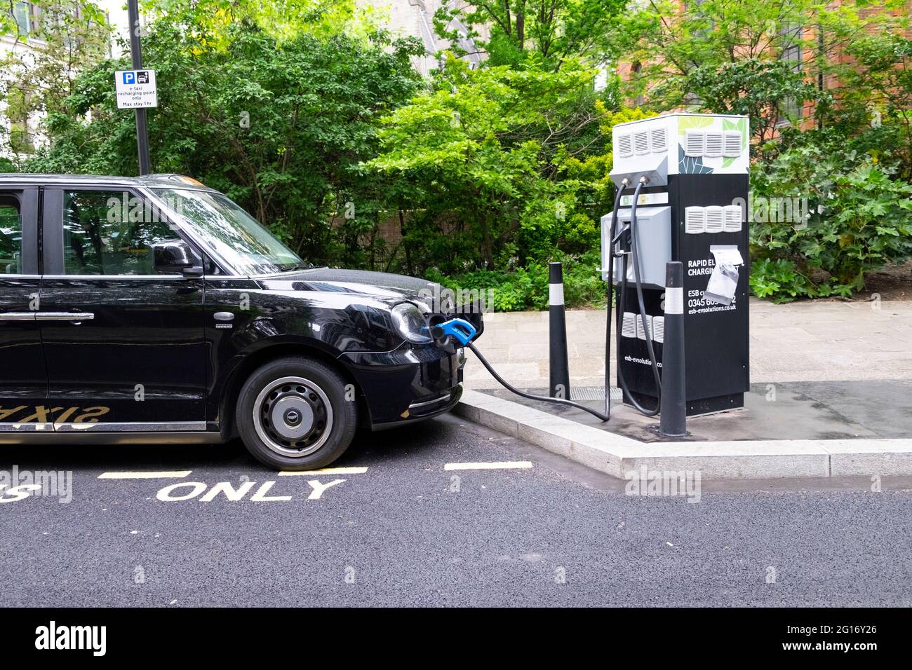 Schwarzes Taxi zum Aufladen des Fahrzeugs an einer elektrischen Ladestation in der City of London England Großbritannien Großbritannien KATHY DEWITT Stockfoto