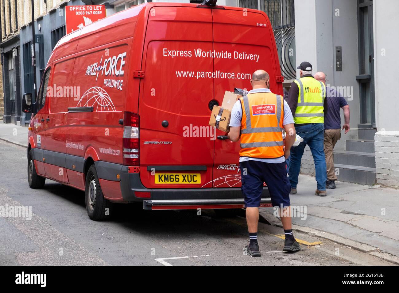 Rückansicht einer Mitarbeiterin der Paketdienste, die Pakete von einem roten Lieferwagen in einer Straße der Londoner City ablieferte London England Großbritannien KATHY DEWITT Stockfoto