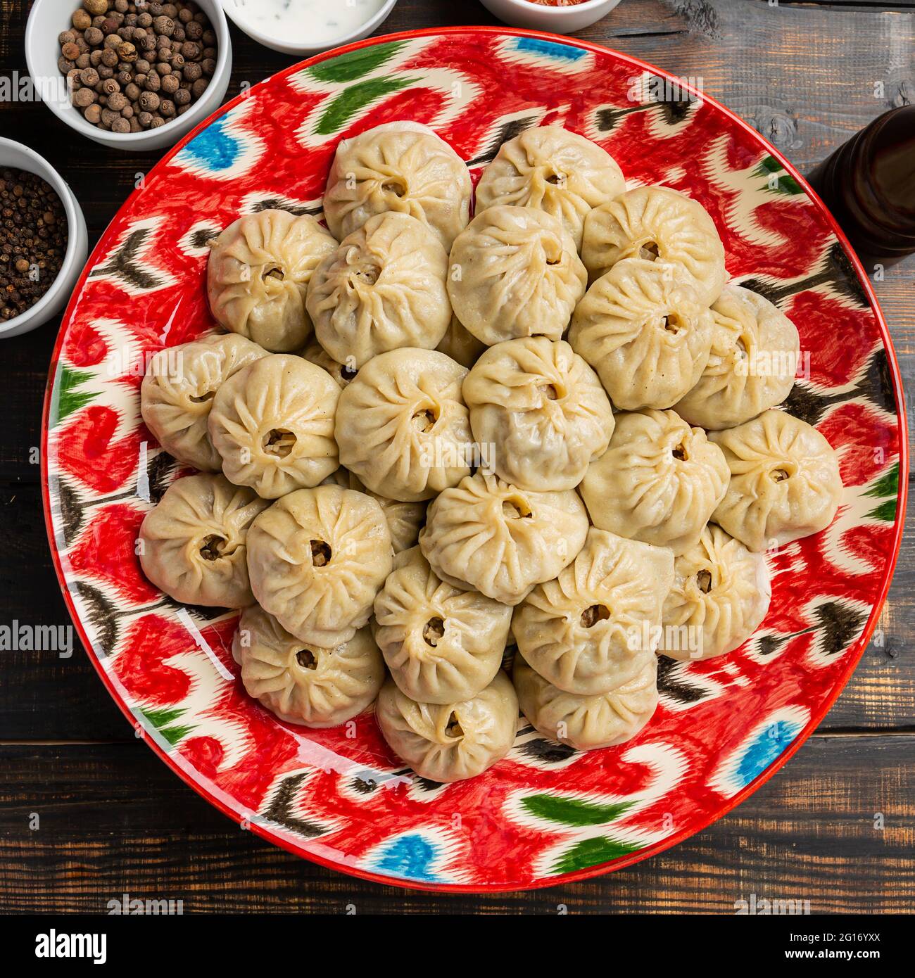 Usbekisch bereitete gekochte Manti- oder Mantelknödel in einer traditionellen Schüssel auf einem rustikalen Holztisch zu. Stockfoto
