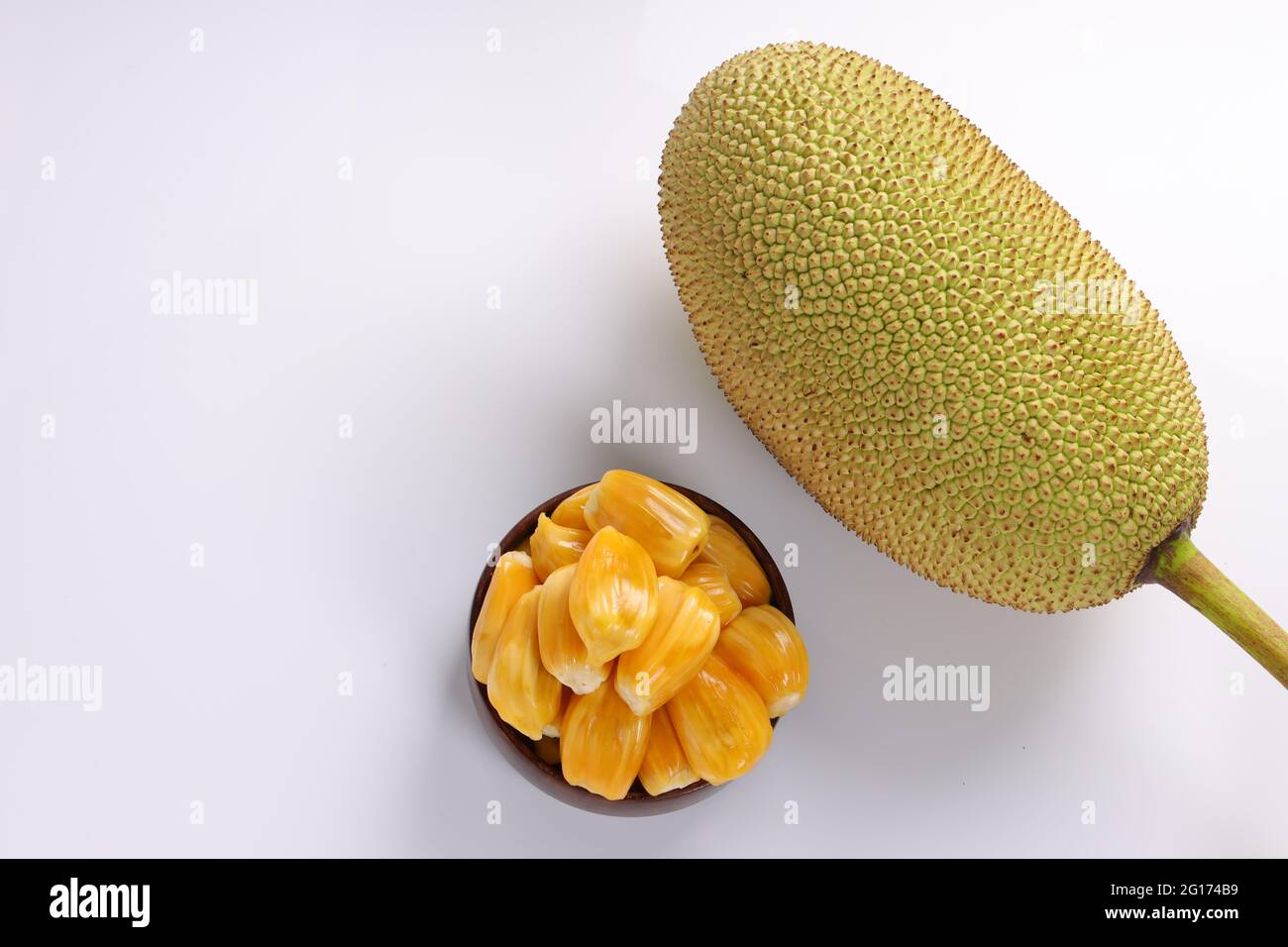 Reife Jackfruit, wunderschön in einer Holzschale mit weißem Strukturhintergrund arrangiert. Stockfoto