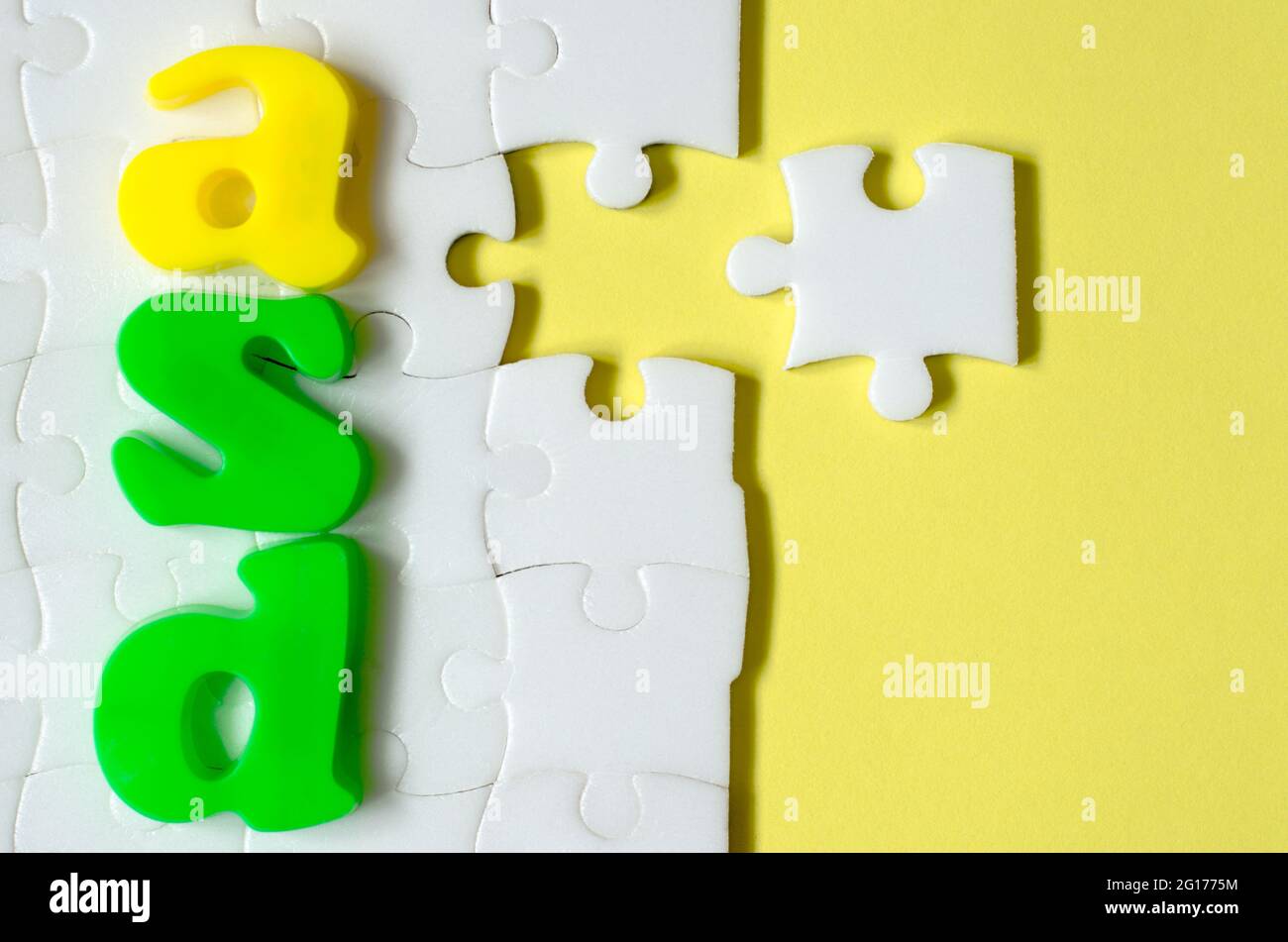 Farbige Buchstaben ASD auf einem Hintergrund von weißen Puzzles. Konzept des Welt-Autismus-Tages Stockfoto