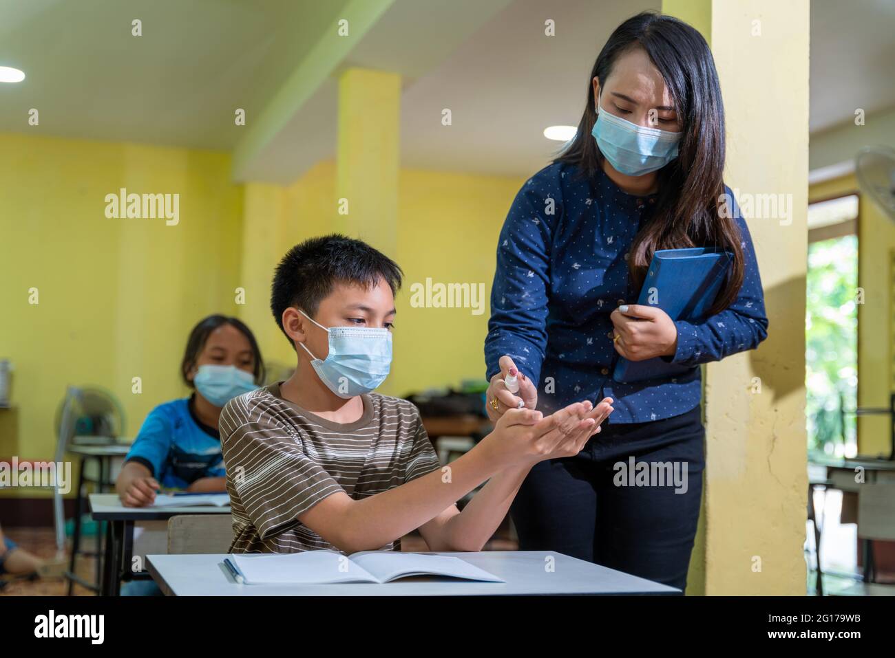 Asiatische Lehrer und Kinder mit Gesichtsmaske zurück in der Schule nach covid-19 Quarantäne und Sperrung und Verwendung von Antiseptikum zur Coronavirus-Prävention. Educa Stockfoto