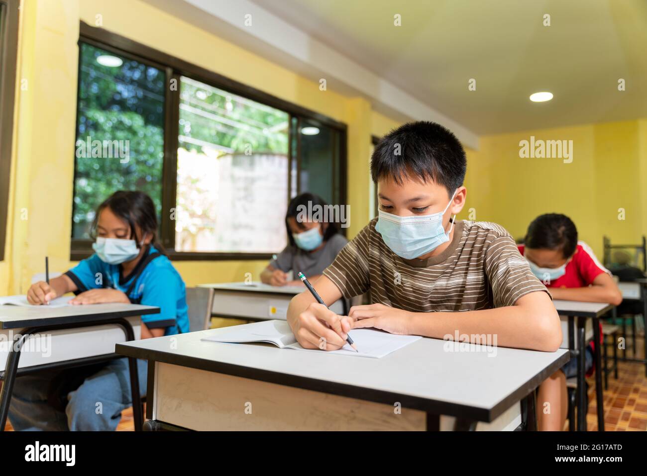 Gruppe asiatischer Kinder, die im Klassenzimmer mit Gesichtsmaske studieren, zurück in der Schule nach covid-19 Quarantäne und Sperrung. Stockfoto