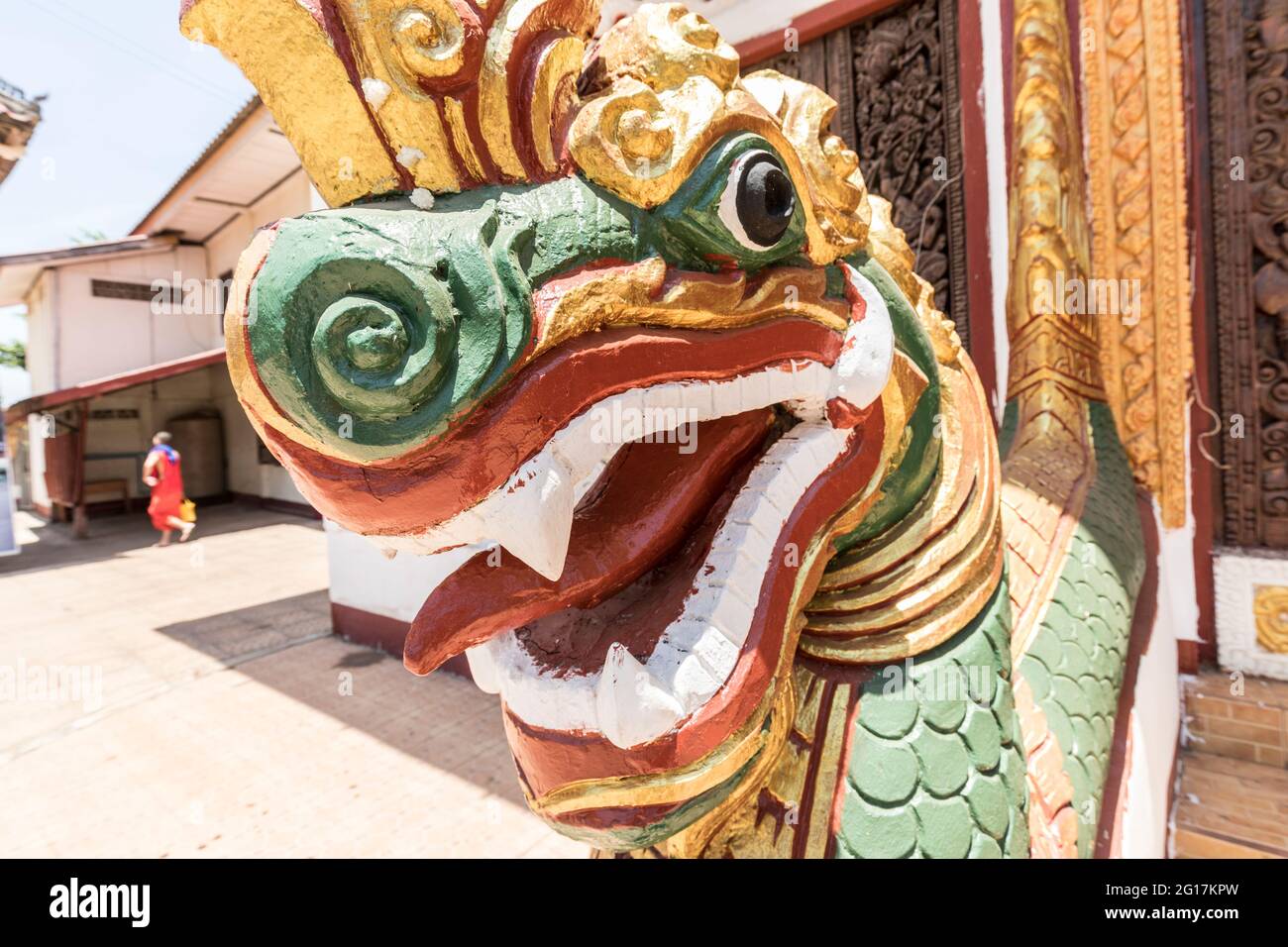 Schlangenkopf vor der Tür zum Wat Luang Pakse, Tempel in Pakse, Laos, mit Mönch im Hintergrund Stockfoto