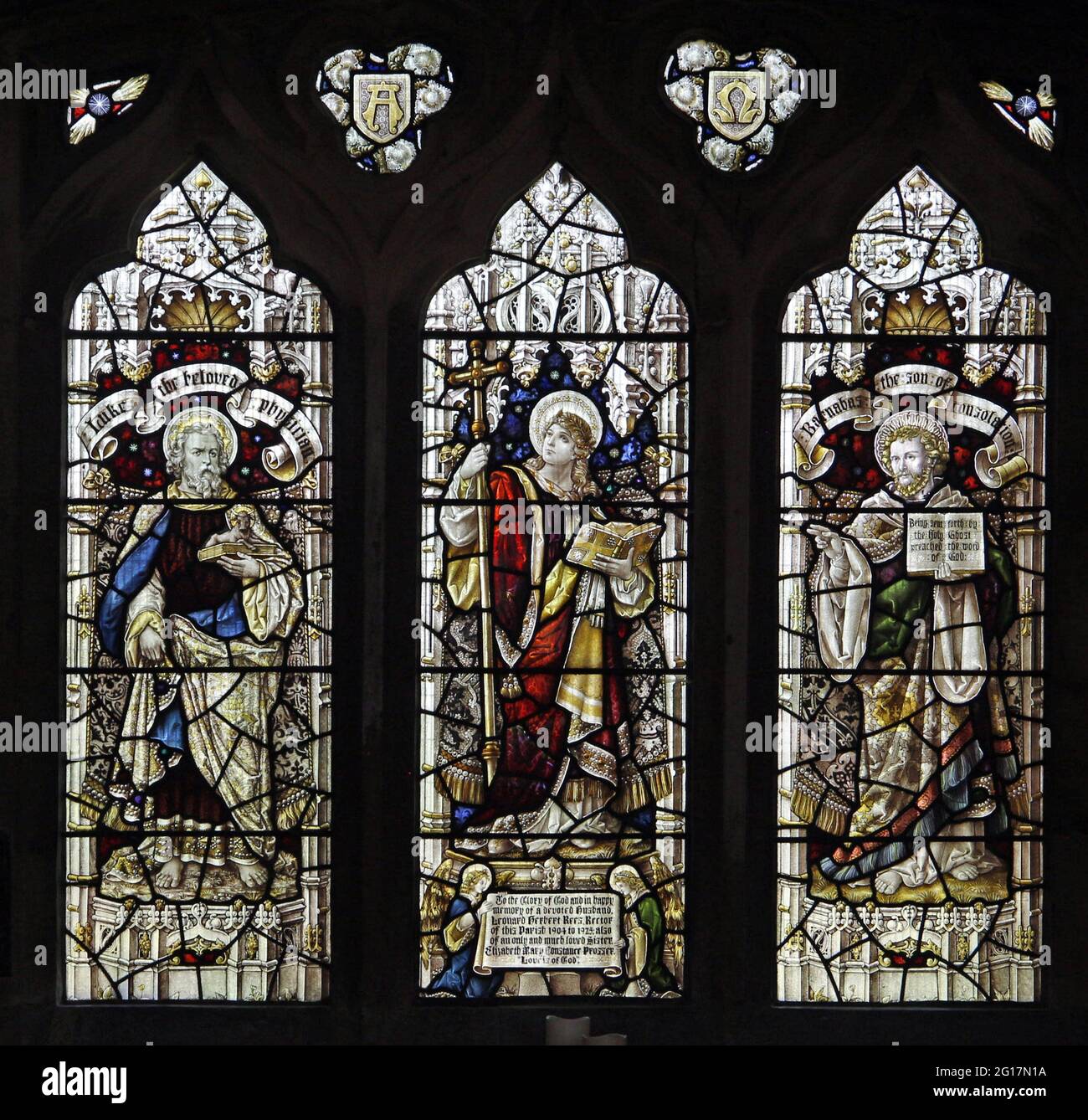 Buntglasfenster von Percy Bacon mit Darstellung von St. Luke, Faith und St. Barnabas, St. Leonard's Church, Rockingham, Northamptonshire Stockfoto