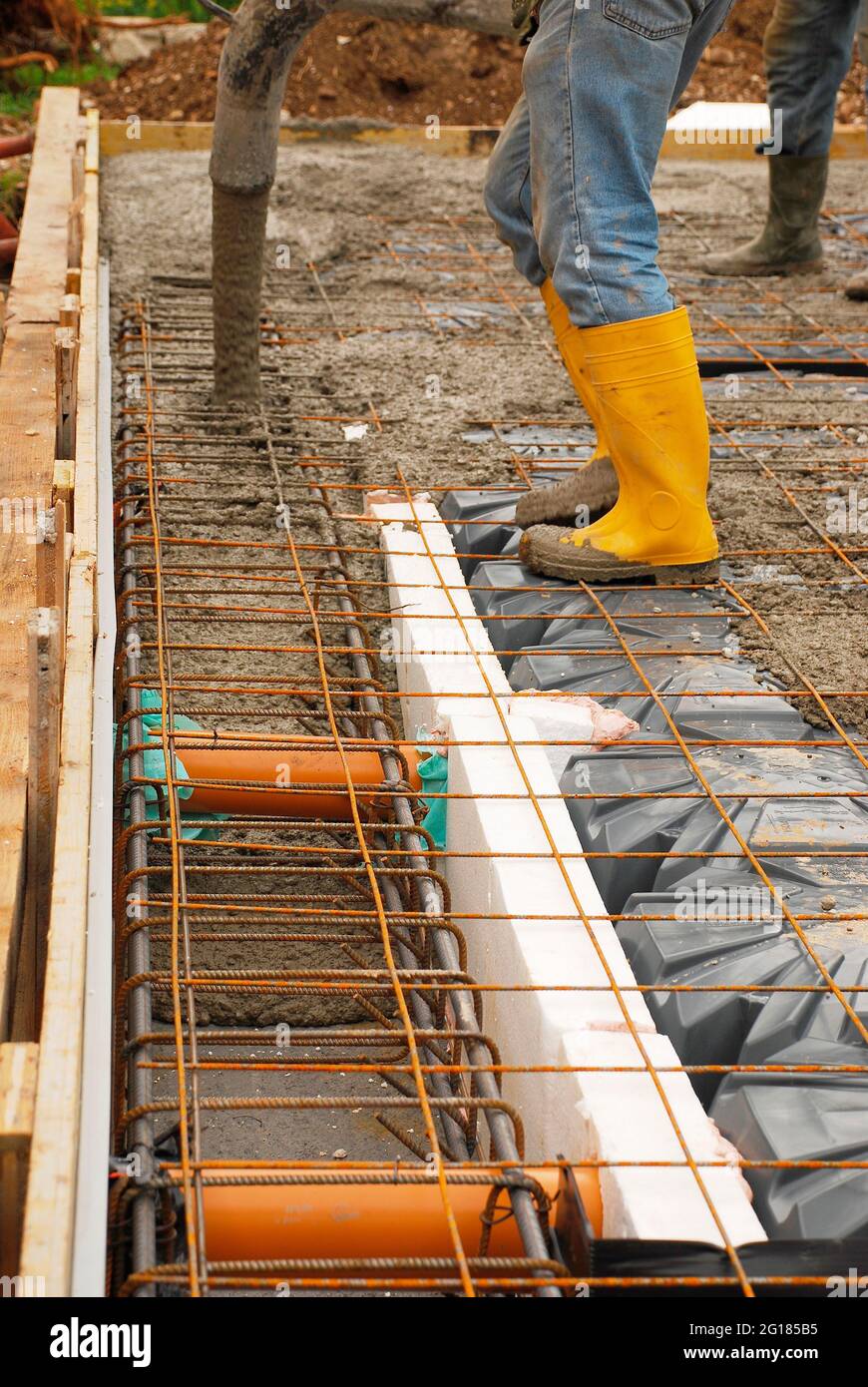 Bauherren gießen Beton auf die Fundamente eines kleinen Hauses. Die Fundamente bestehen aus Stahlverstärkungskäfigen und -Maschen sowie Radon iglus. Udine, IT Stockfoto