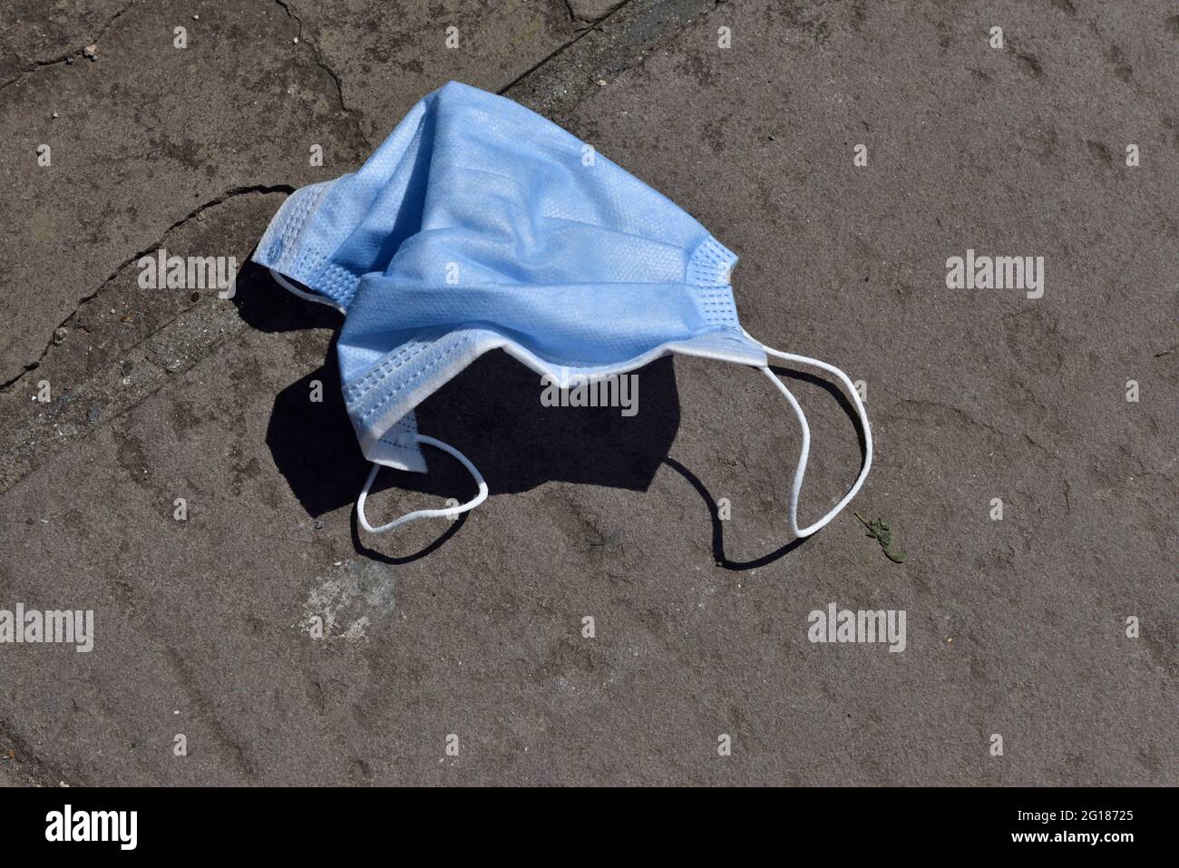 Einweg-Gesichtsmaske auf dem Bürgersteig weggeworfen Stockfoto