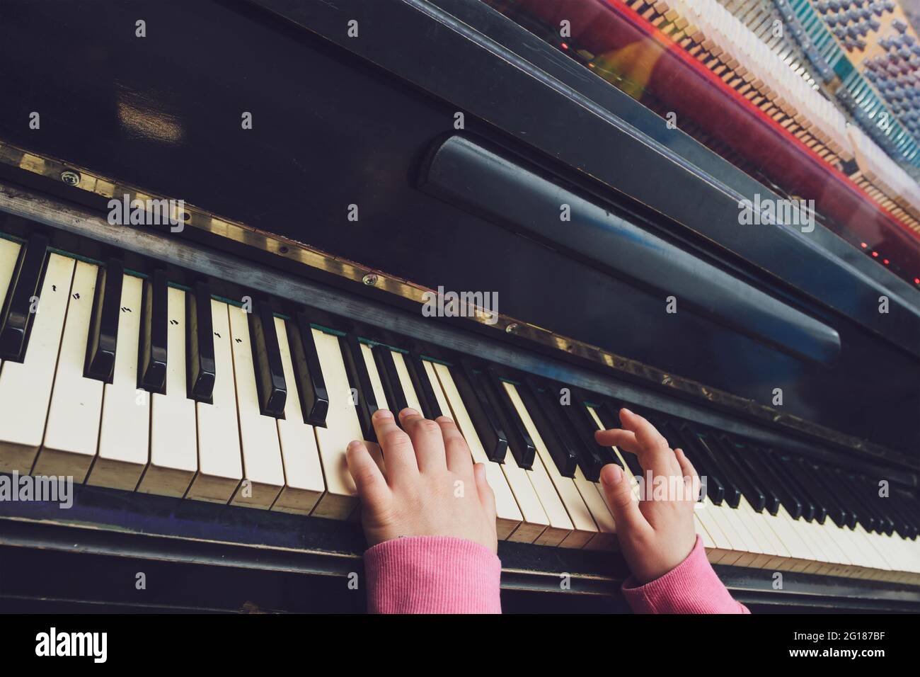 Kinderhände auf den Tasten des alten Klaviers. Stockfoto