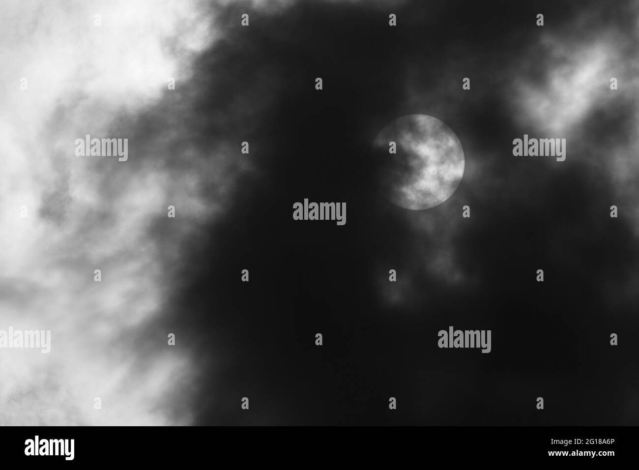 Schwarz-Weiß-Foto der Sonne hinter dunklen Wolken Stockfoto