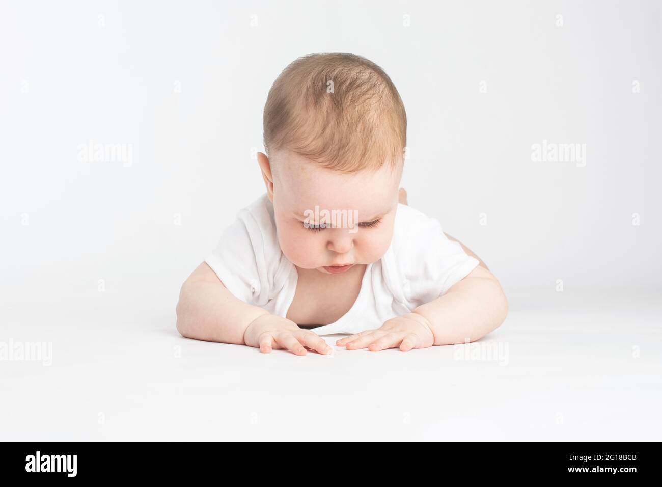 Baby schaut auf den Boden, auf einem weißen Hintergrund Stockfoto