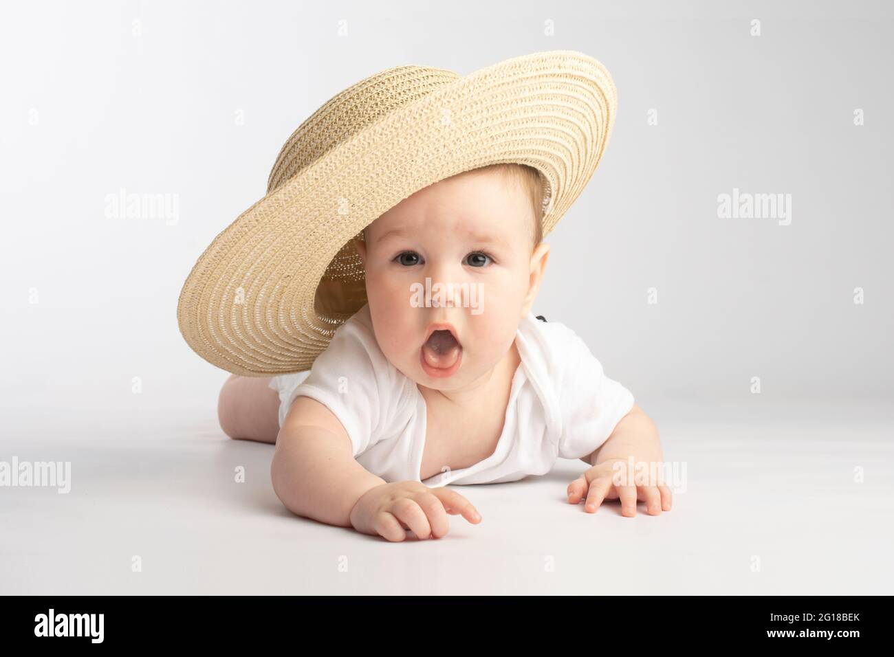 Niedliches Baby in einem großen Strohhut, auf weißem Hintergrund  Stockfotografie - Alamy
