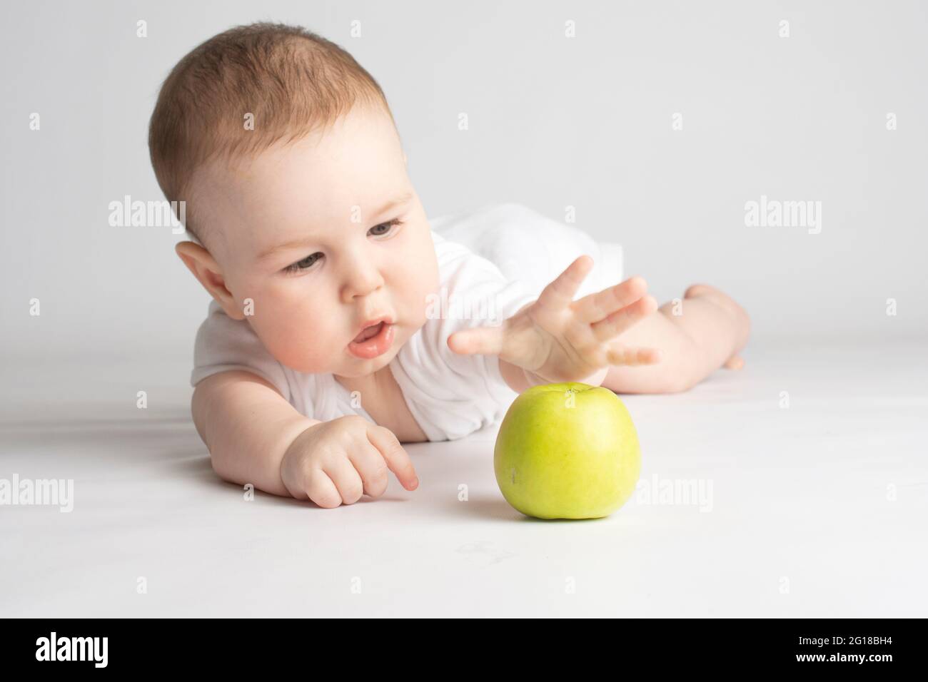 Das Kind greift nach einem grünen Apfel Stockfoto