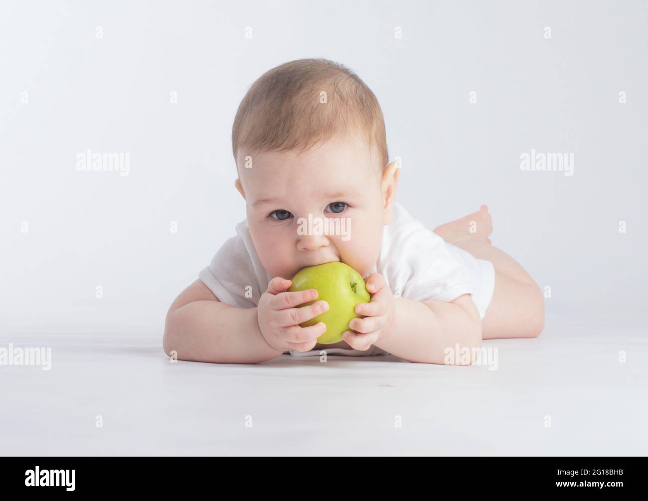 Nettes Baby essen grünen Apfel, auf weißem Hintergrund Stockfoto