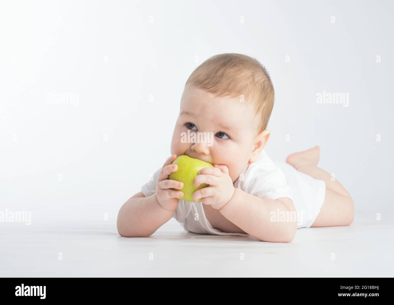 Nettes Baby essen grünen Apfel, auf weißem Hintergrund Stockfoto