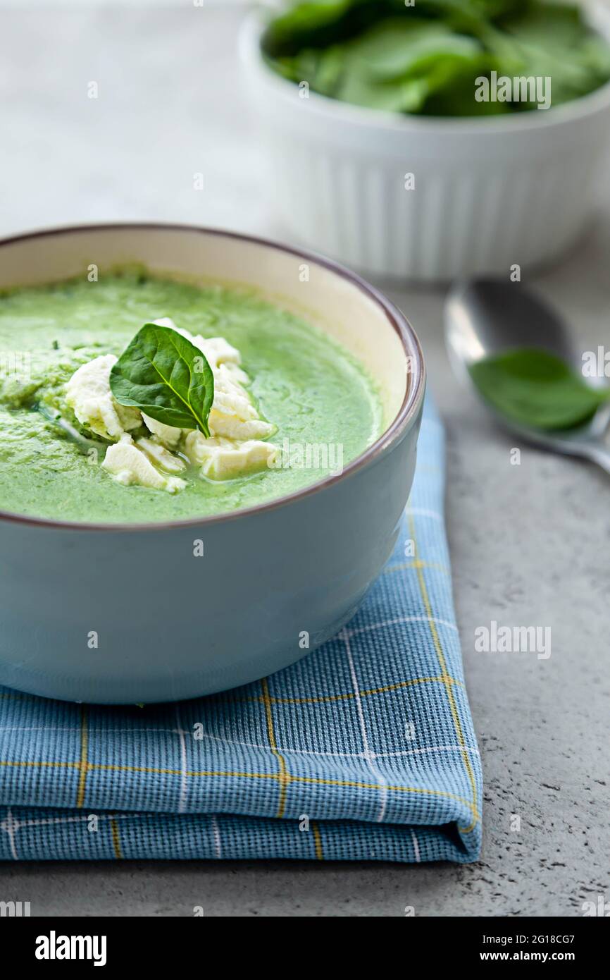 Grüne Sahnesuppe in einer blauen Schüssel auf einem steinernen grauen Tisch. Im Sommer Mittag- oder Abendessen. Stockfoto