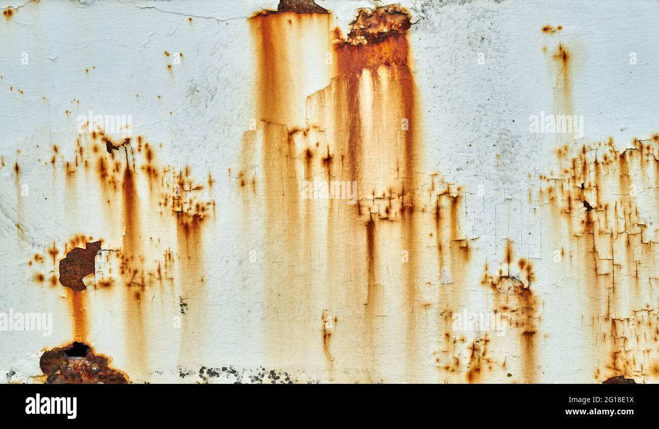 Flecken von Rost und abblätternder Farbe an einer weißen Wand Stockfoto