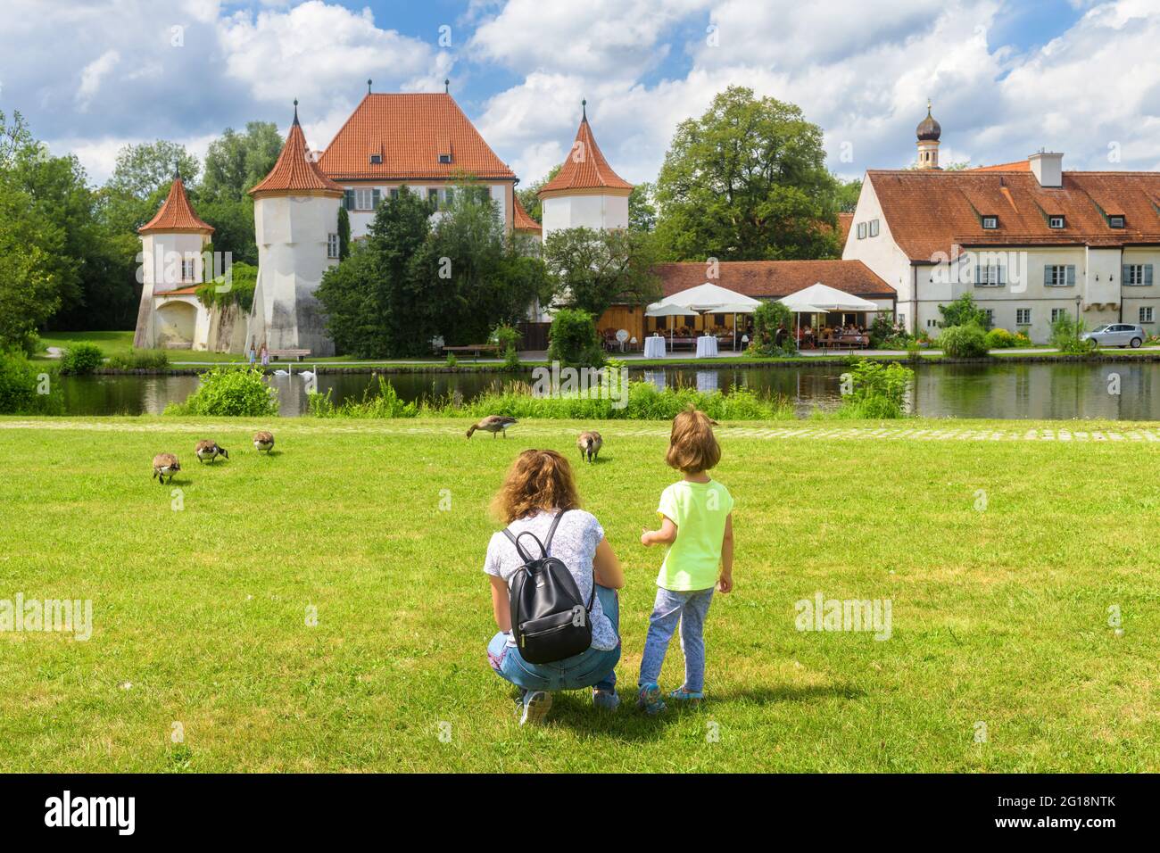 Kinderspaziergänge auf grüner Wiese am alten Schloss Blutenburg, München, Bayern, Deutschland. Familie im Stadtpark im Sommer. Dieser Ort ist Touristenattraktion von Munic Stockfoto