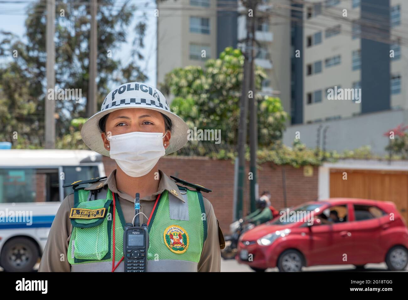 Vorderansicht mittellanges Porträt einer jungen und attraktiven peruanischen Polizistin mit einer OP-Maske in Lima, Peru während der COVID-19 Pandemie. Stockfoto