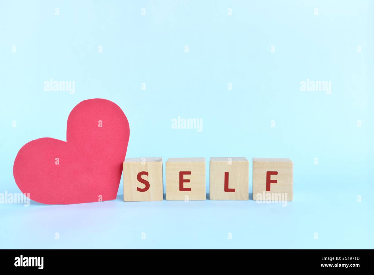 Selbstliebe und Pflege Konzept. Holzblöcke Typografie mit großen roten Herz Form Ausschnitt. Stockfoto