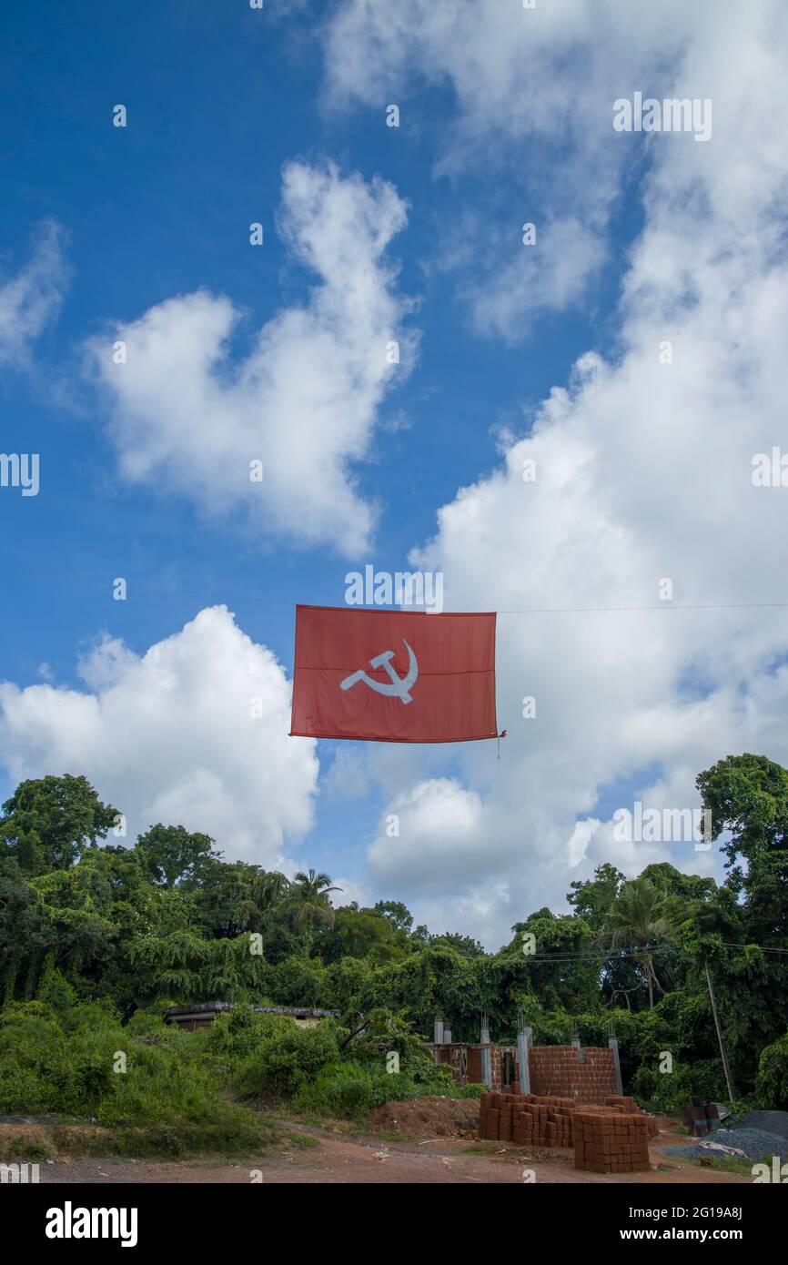 kommunistische Flagge. Hammer und Sichel, die die Bauern und die Arbeiter darstellen, fliegen im dichten, wolkigen blauen Himmel. Stockfoto