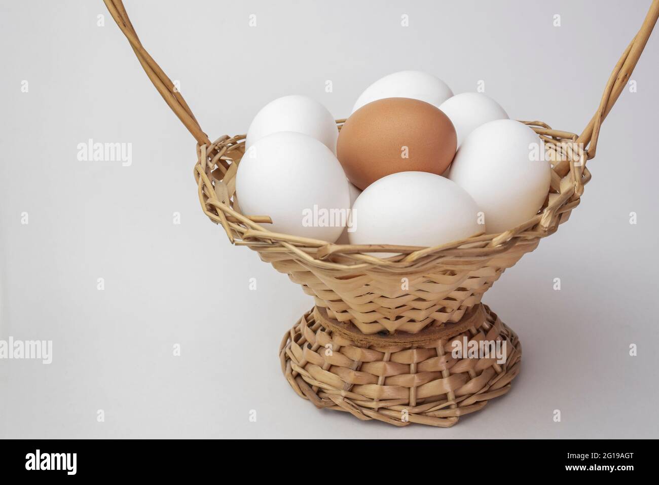 Mehrere weiße und ein braunes Ei in einem Korb. Ländliche Szene. Osterhintergrund - frische Hühnereier. Konzept ist nicht wie alle anderen. Stockfoto