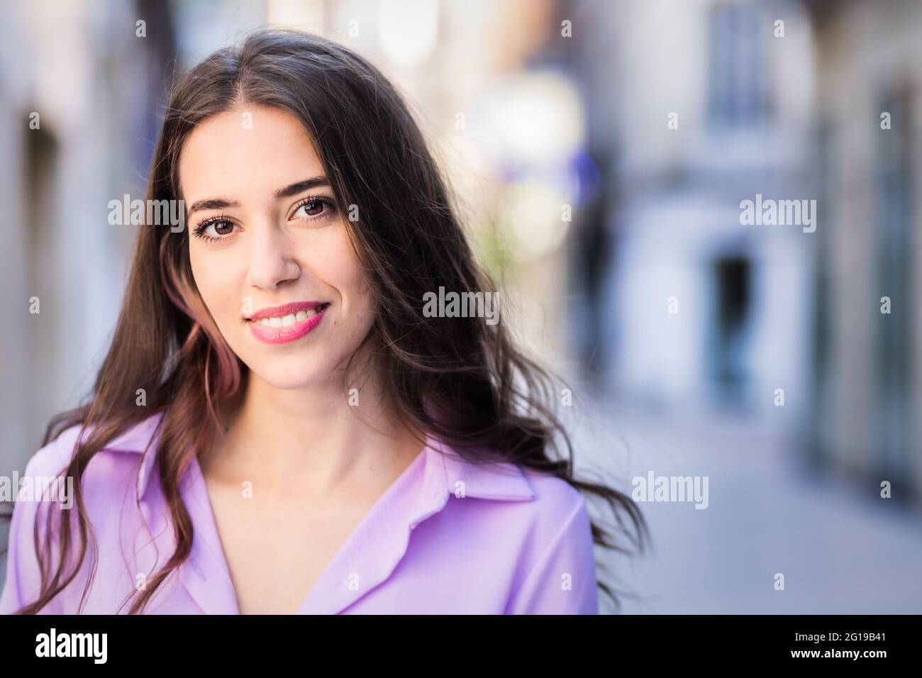 Schöne hispanische unabhängige junge Frau Lifestyle Stadtportrait. Lavendel Streetwear stylisch in der Kamera. Echte Menschen Stockfoto