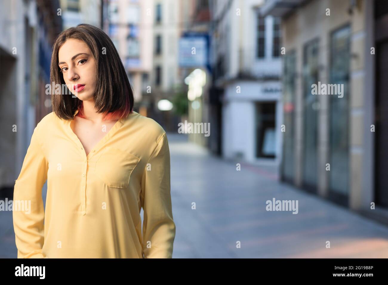 Junge hispanic unabhängige und selbstbewusste Frau in einer städtischen Straße in Toledo, Spanien. Lifestyle Streetwear Portrait Gelb Farbe des Jahres stylisch Stockfoto