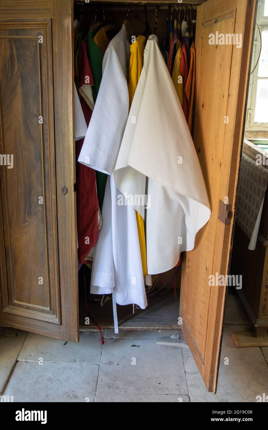 Die Gewänder flattern in einem offenen Schrank in der Sakristei einer Landkirche Stockfoto