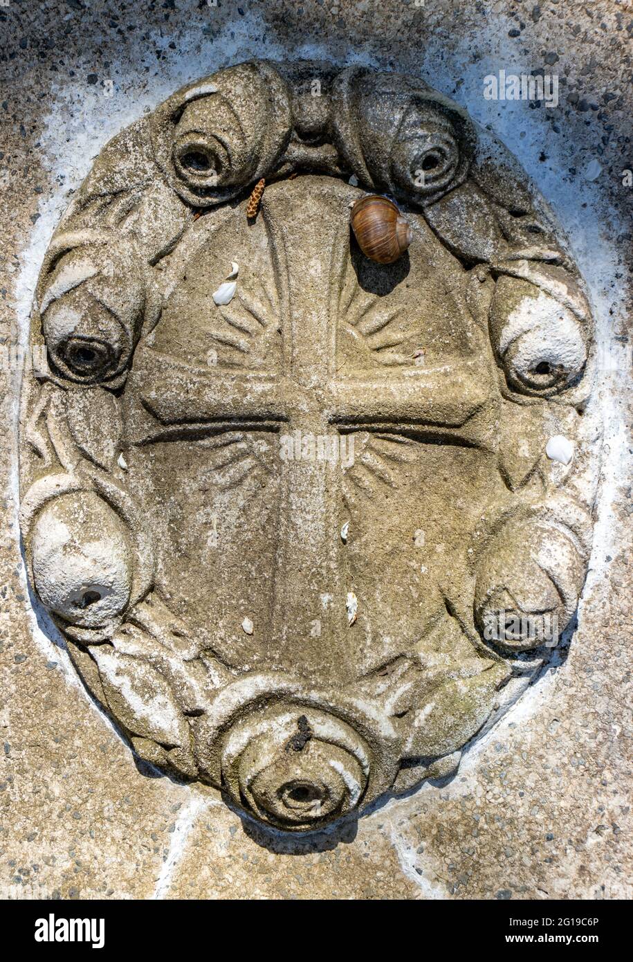Christian Kreuz auf einem Grabstein mit einer Schnecke, Nahaufnahme. Stockfoto