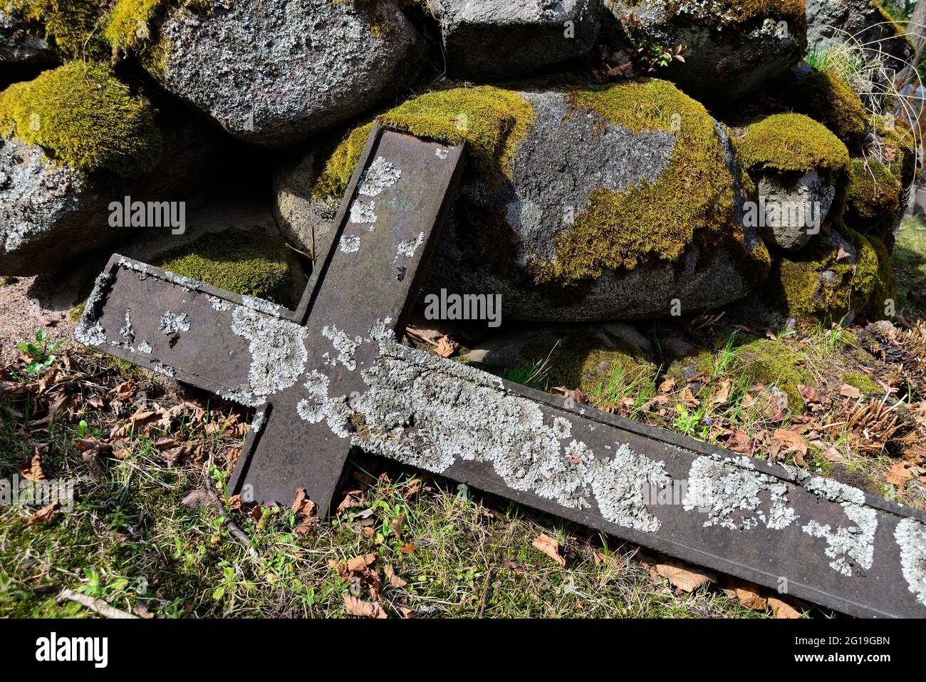 Ein gefallenes Kreuz und ein Haufen Moos bedeckten Steine auf einem alten Friedhof Stockfoto
