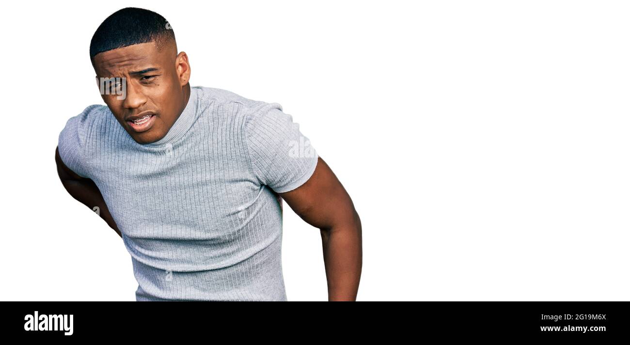 Junger schwarzer Mann in einem lässigen T-Shirt mit Rückenschmerzen,  Berührung des Rückens mit der Hand, Muskelschmerzen Stockfotografie - Alamy
