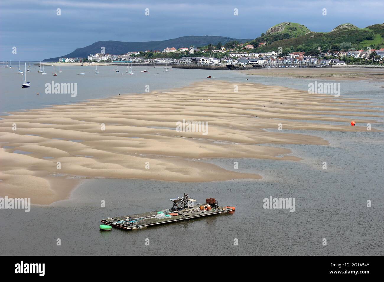 Gezeitensandbänke in der Mündung des Conway bei Low Tide, Muschelsortierbarge im Vordergrund, Deganwy im Hintergrund Stockfoto