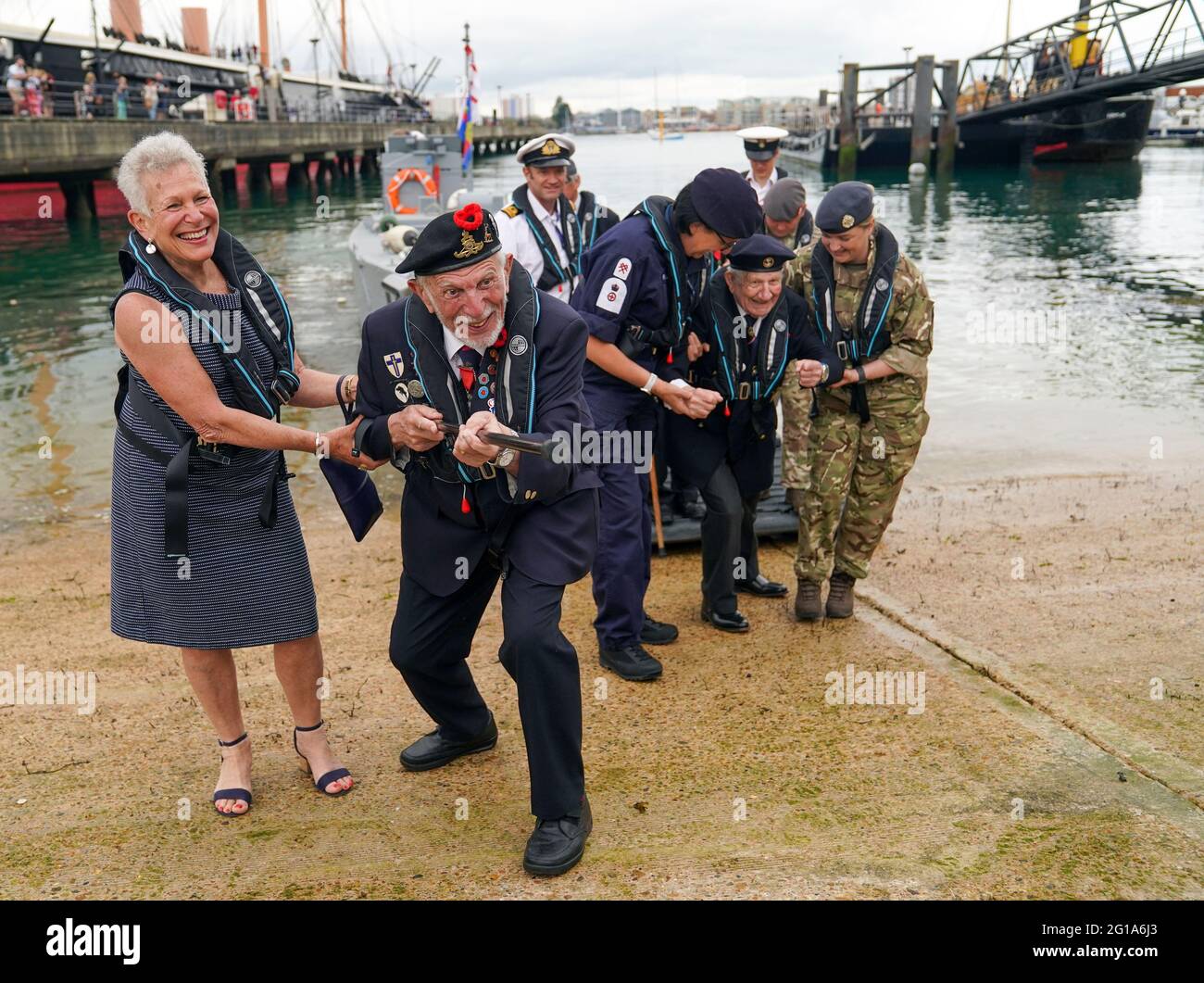 Joe Cattini, Veteran des D-Day, hebt seinen Spazierstock wie ein Maschinengewehr, während er und andere Veteranen in der historischen Hafenanlage von Portsmouth begrüßt werden, um an den 77. Jahrestag der Landung in der Normandie zu erinnern. Bilddatum: Sonntag, 6. Juni 2021. Stockfoto