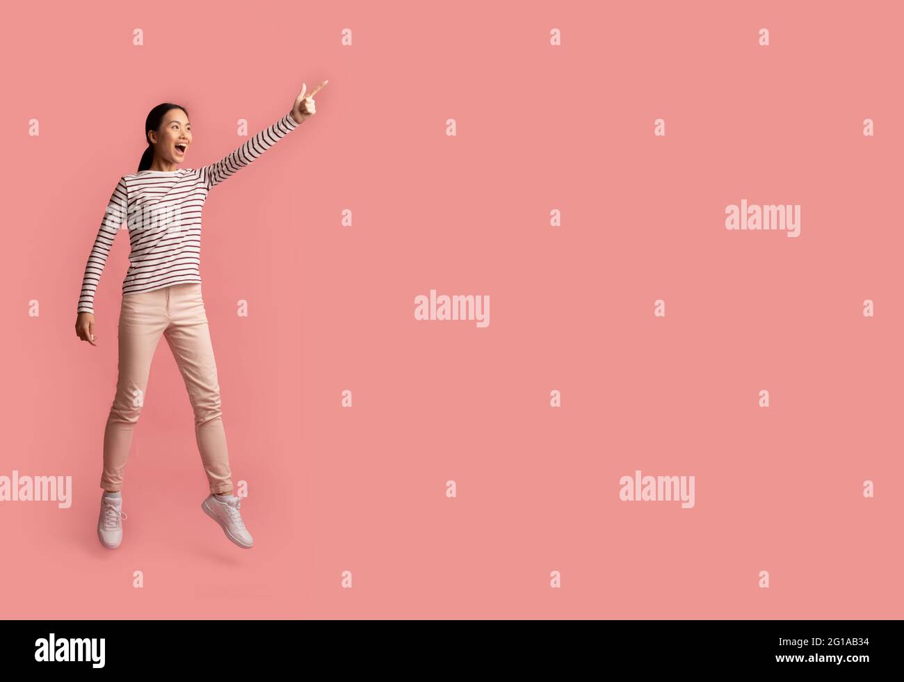 Tolles Angebot. Aufgeregt Junge Asiatische Frau Springen Und Zeigen Auf Copy Space Stockfoto
