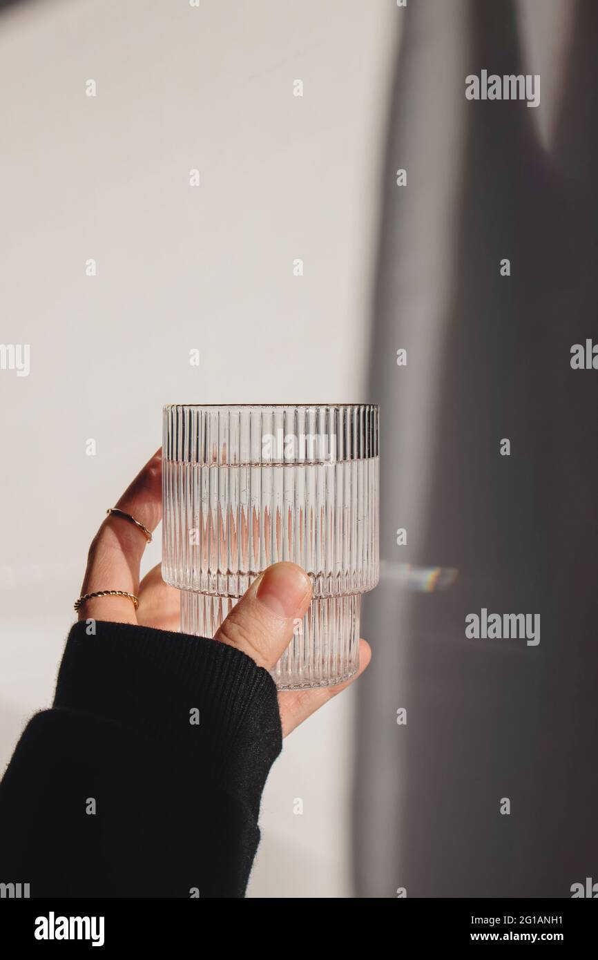 Frau Hand hält ein Glas sauberes Wasser über die Weiße Wand Stockfoto