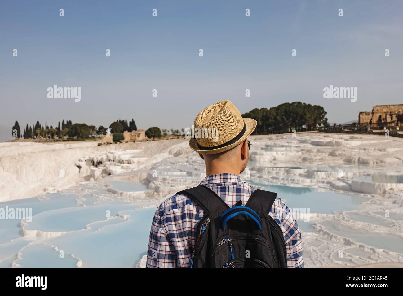 Junger männlicher Tourist in Strohhut, der auf die natürlichen Travertin-Pools schaut Stockfoto