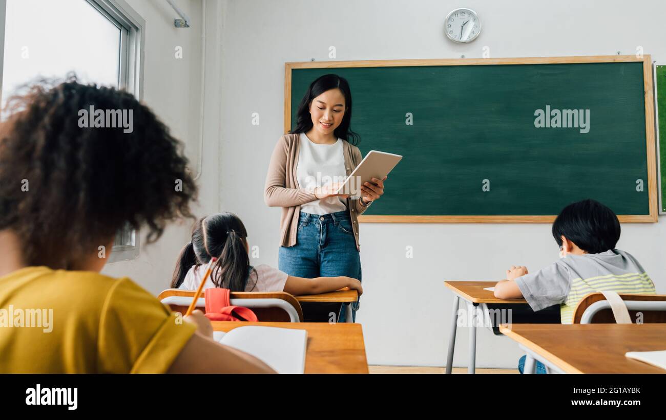 Asiatische Schullehrer mit digitalen Gerät mit Kindern im Klassenzimmer in der Schule, Technologie, Lernen, Entwicklung. Stockfoto