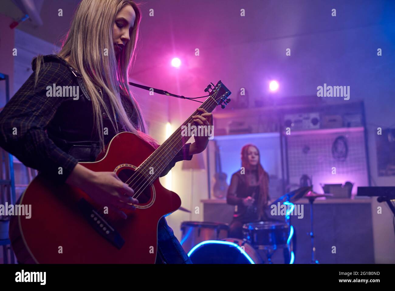 Hübsche blonde Frau, die während der Bühnenperformance E-Gitarre spielt Stockfoto