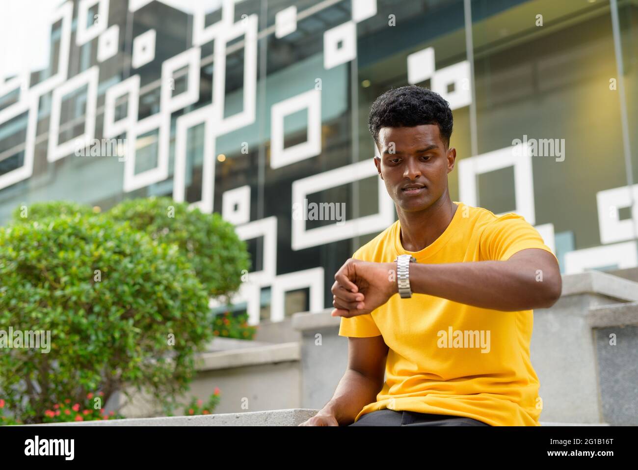 Porträt eines hübschen schwarzen afrikanischen Mannes, der im Freien in Bangkok, Thailand, ein gelbes T-Shirt trägt Stockfoto