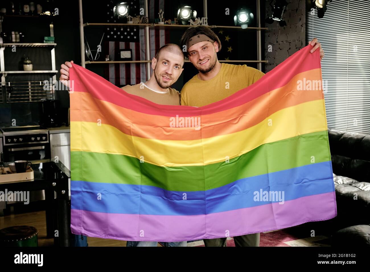 Junge liebevolle homosexuelle Paar mit Regenbogenfahne Stockfoto