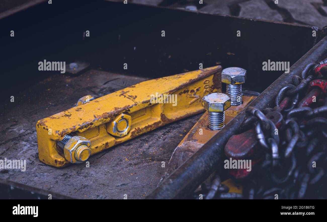 Schwere Eisen- und Metallwerkzeugteile auf einer Baustelle. Werkzeuge und Schrauben aus einem Bagger als Stillleben in einem coolen Stil. Stockfoto