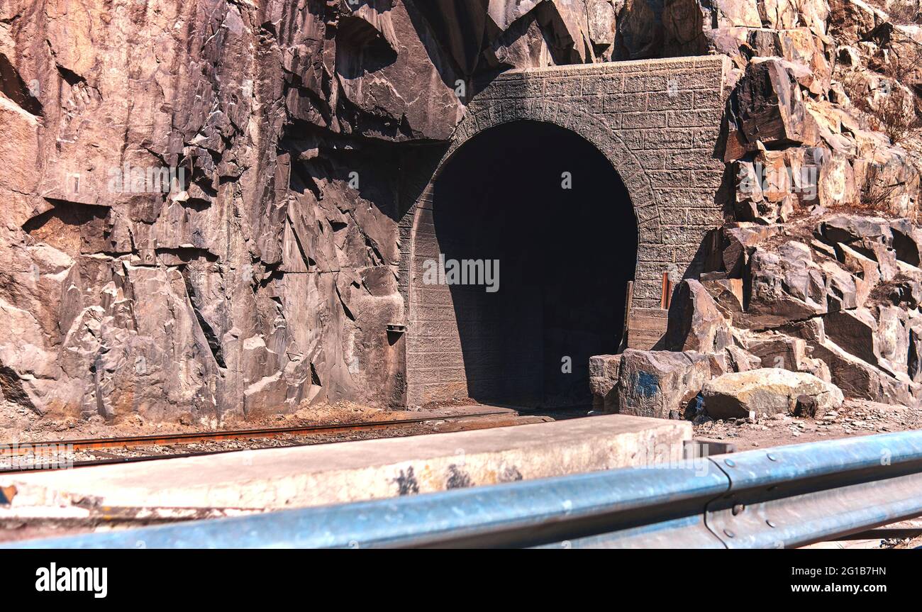 Schöne Aufnahme von Eisenbahnschienen, umgeben von Natur, die zum dunklen Tunnel führt Link × Titel: Schöne Aufnahme von Eisenbahnschienen, umgeben von Natur, die führt Stockfoto