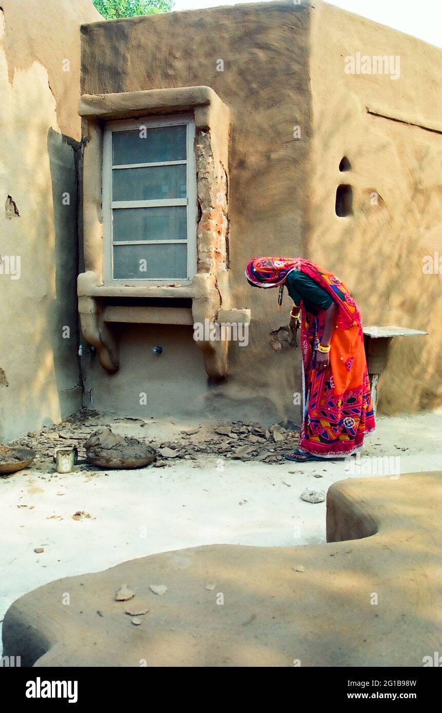 Im Wüstencamp in Mandawa (Rajasthan) gehen Frauen in bunten Ghagra-Cholis ihre Geschäfte mit dem Verputzen der Wände und der Reparatur der Hütten durch. Indien. 2004. Stockfoto