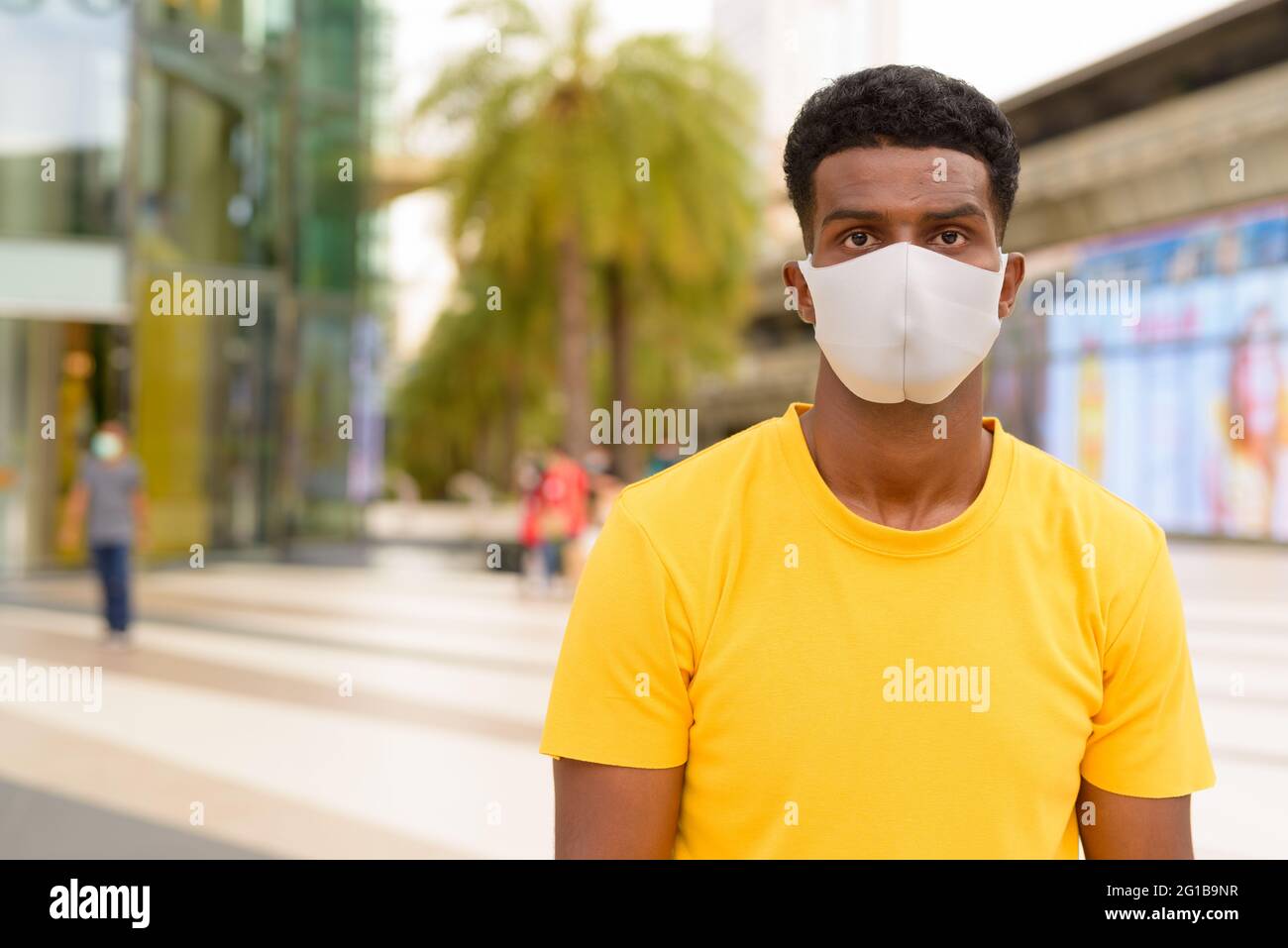 Porträt eines hübschen schwarzen afrikanischen Mannes, der im Freien in Bangkok, Thailand, ein gelbes T-Shirt trägt Stockfoto