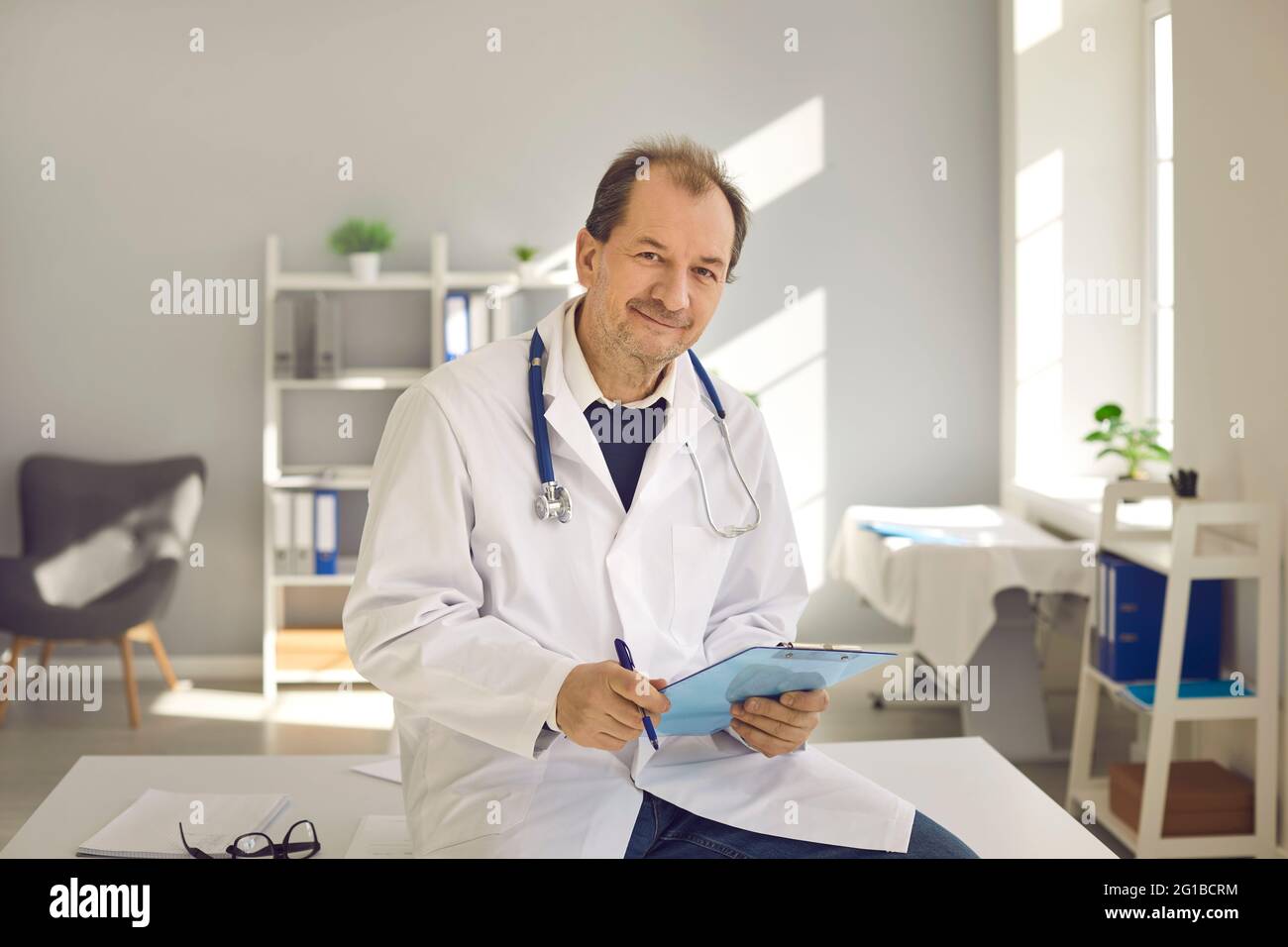 Porträt eines erfahrenen männlichen Oberarztes mit Dokumenten in den Händen im Klinikbüro. Stockfoto