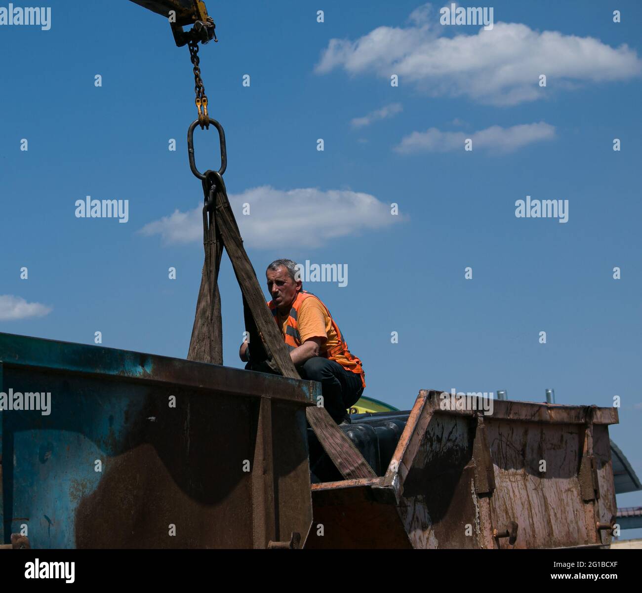 Dnepropetrovsk, Ukraine - 05.28.2021: Müllcontainer mit einem Kran in einen LKW laden. Slinger funktioniert. Stockfoto