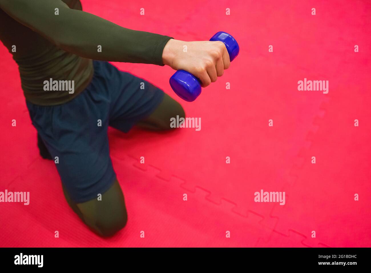 Der Typ in einem thermischen Anzug und Shorts macht Übungen mit Kurzhanteln im Fitnessstudio. Stockfoto