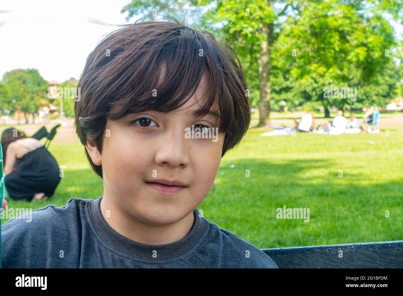 Porträt eines Jungen draußen im Park. Er hat eine gemischte asiatische und weiße Herkunft. Stockfoto