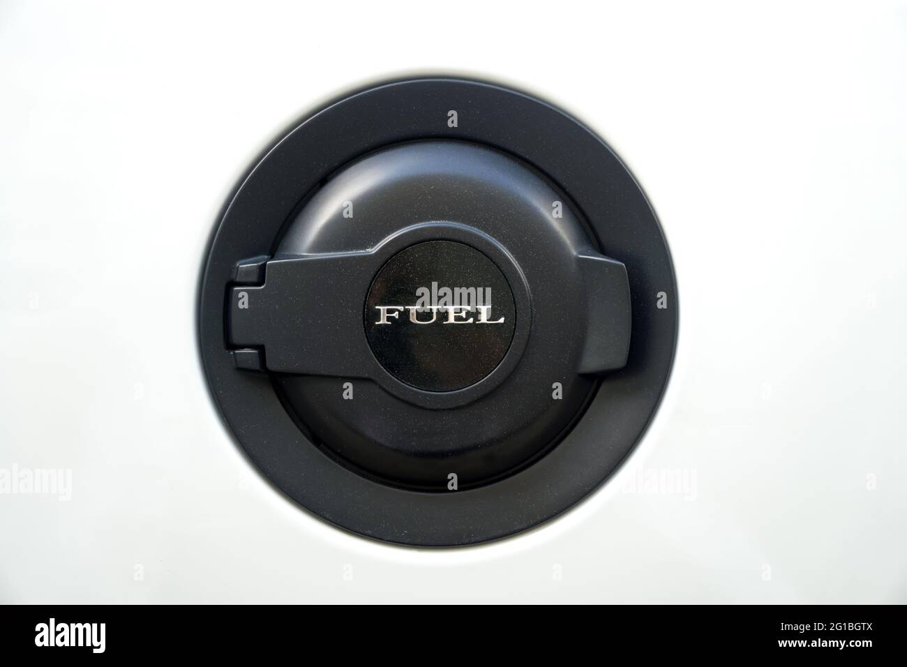 Schwarze Tankklappe mit Schriftzug „FUEL“ auf einem weißen Auto. Nahaufnahme. Stockfoto